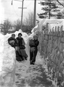 Women and children beside rock wall