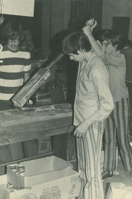 Boys using can crusher at recycling depot