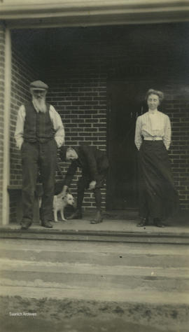 Man, woman and boy with dog on a porch