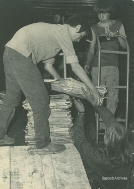 Boys handling newspapers at recycling depot